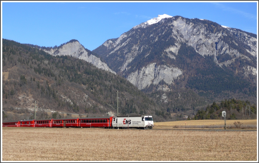 Der RE1145 mit Ge 4/4 III 643  Vals  hat die Ebene bei der Kapelle Sogn Mang erreicht. Im Hintergrund Kunkelspass, Sennenstein und Taminser Calanda 2389m, wo der letzte Februarschnee zu sehen ist. (08.02.2011)