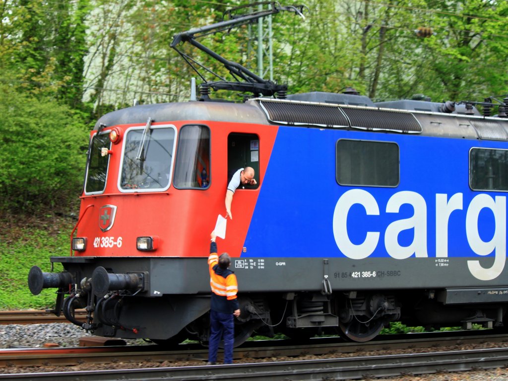 Der Tf der 421 385-6 mu am 03.05.2012 bei der Ausfahrt aus Aachen West beherzt zugreifen um seine Papiere zu bekommen. Ein Mitarbeiter der SBB stellt sich mit den Papieren ans Gleis und hlt sie dem Tf der mit einem Containerzug bespannten Lok hoch, der dann nur zugreifen mu. Dadurch wird enorm viel Zeit gespart, man braucht nicht mehrere hundert Meter mit den Papieren unter dem Arm durch die Gleisanlagen zu laufen um bis zur Lok zu gelangen, sondern wartet bis der Zug langsam in der nhe des Bros in dem die Papiere bearbeitet werden vorbeifhrt. 