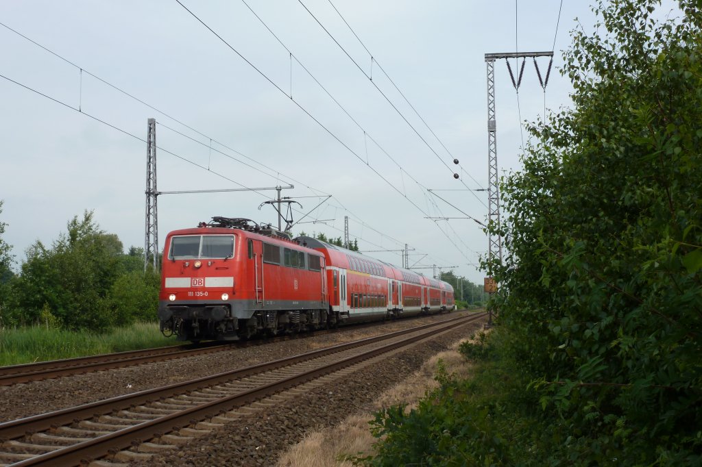 Die 111 135-0 fuhr am 11.06.2012 mit einem RE von Emden nach Mnster, hier bei Neermoor.