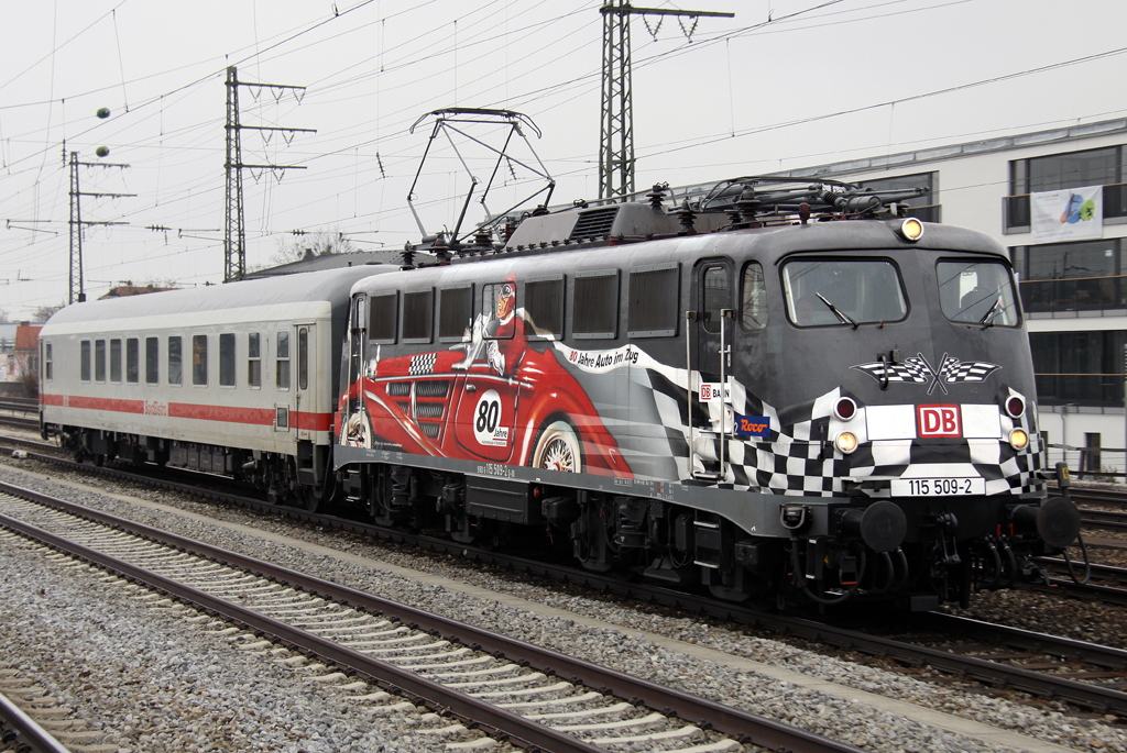 Die 115 509-2 mit sauberer 80 Jahre DB Autozug Beklebung zieht PbZ 2460 nach Stuttgart durch Pasing am 06.04.2013