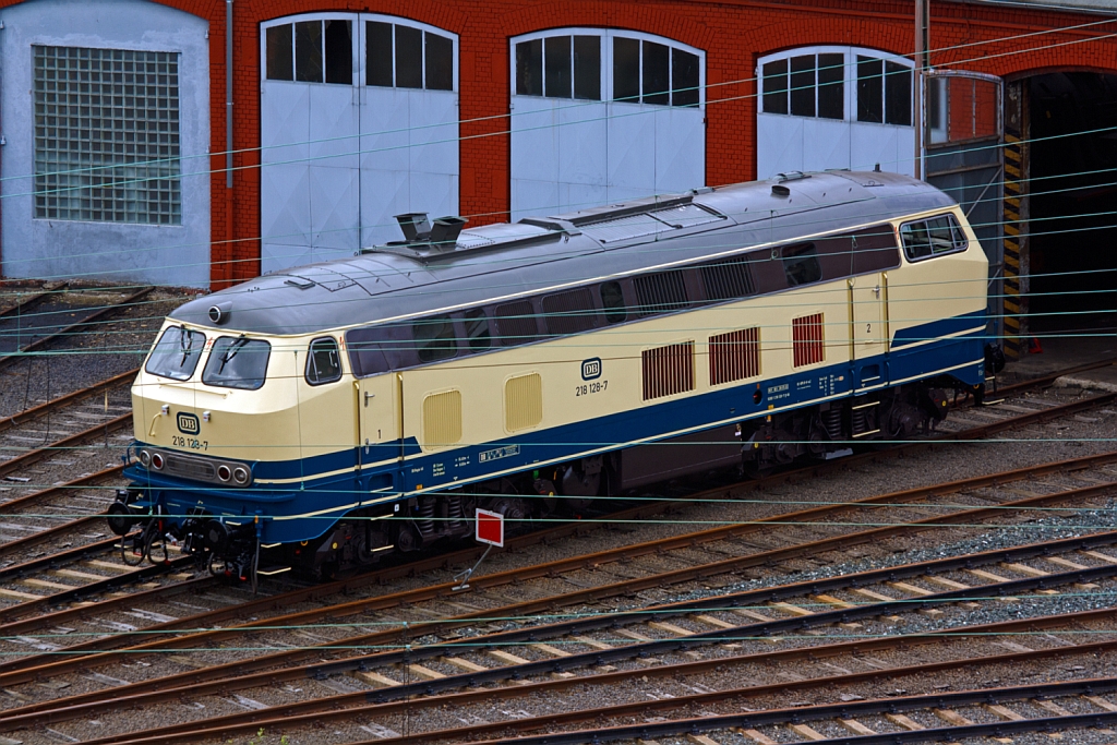 Die 218 128-7 steht am 21.07.2012 vor dem Siegener Lokschuppen, Blick vom Parkdeck der City Galerie.
Die Lok wurde 1971/72 bei Krupp unter der Fabriknummer 5149 gebaut, die Ausmusterung erfolgte am 27.05.2010.
Sie hat einen MTU-Motor vom Typ 12 V 956 TB 10  mit 1839 kW/ 2500 PS Leistung, die Hchstgeschwindigkeit betrgt 140 km/h.