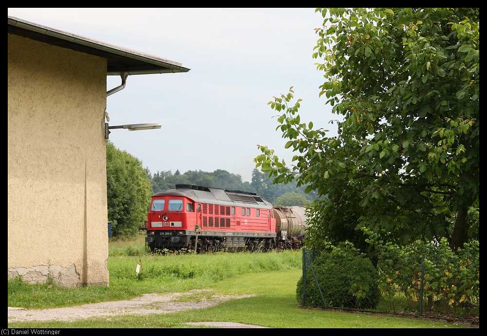 Die 233 289 dieselt am 12. August 2010 mit einem Gterzug durch den Bahnhof Tssling. Im Vordergrund steht das Stellwerk der Bahnhofsausfahrt in Richtung Freilassing und Burghausen.