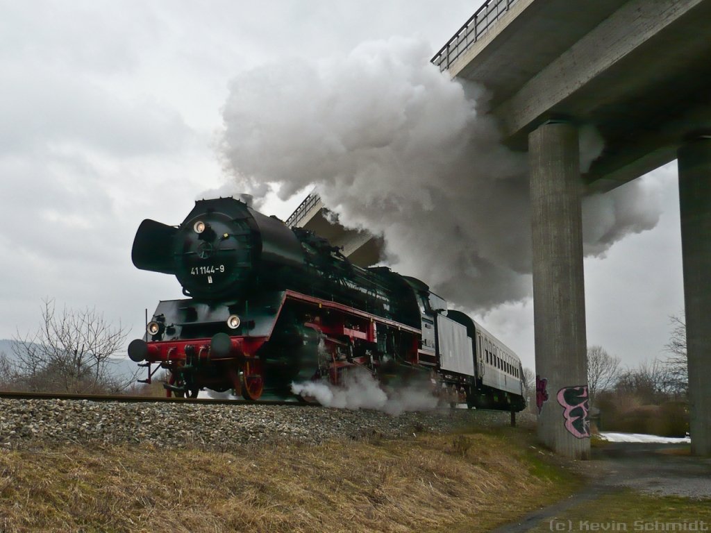 Die 41 1144-9 nähert sich dampfend mit einem Sonderzug aus Richtung Erfurt dem Bahnhof Saalfeld (Saale). Die historische Lok unterquert hier eine moderne Schnellstraßenbrücke. (12.03.2010)