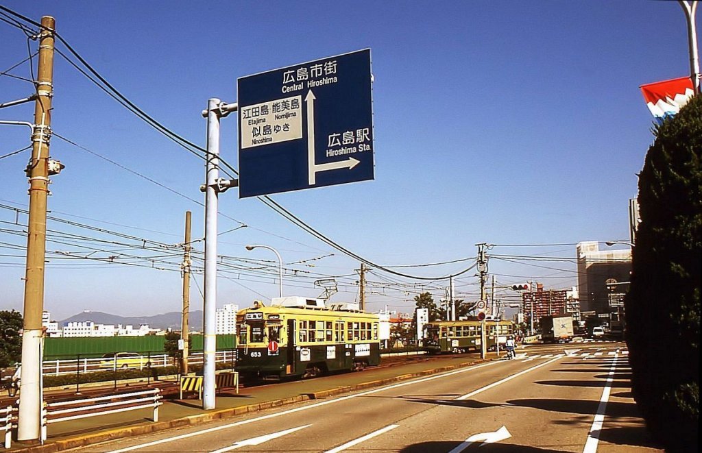 Die ältesten Strassenbahnwagen von Hiroshima - die Wagen, die die Atombombe erlebt haben, Serie 651: Wagen 653 wurde 2006 ausgemustert. Hier kommt er zum Hafen von Hiroshima in Ujina, während der Wagen aus Kôbe Nr.1103 im Hintergrund davonfährt. 11.Oktober 1996.  