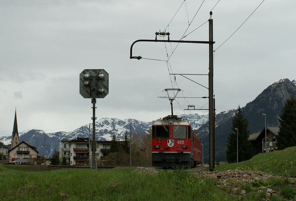 Die alten, wohl noch aus der Zeit der Elektrifizierung stammenden, typischen RhB Fahrleitungsmasten findet man nur noch vereinzelt und nicht mehr lange zwischen Davon Platz und Davos Monstein. 
Auf dem Bild erreicht der Regionalzug 1832 mit der schiebenden Ge 4/4 II 622 am 11. Mai 2010 in Kürze Davos Platz.  
