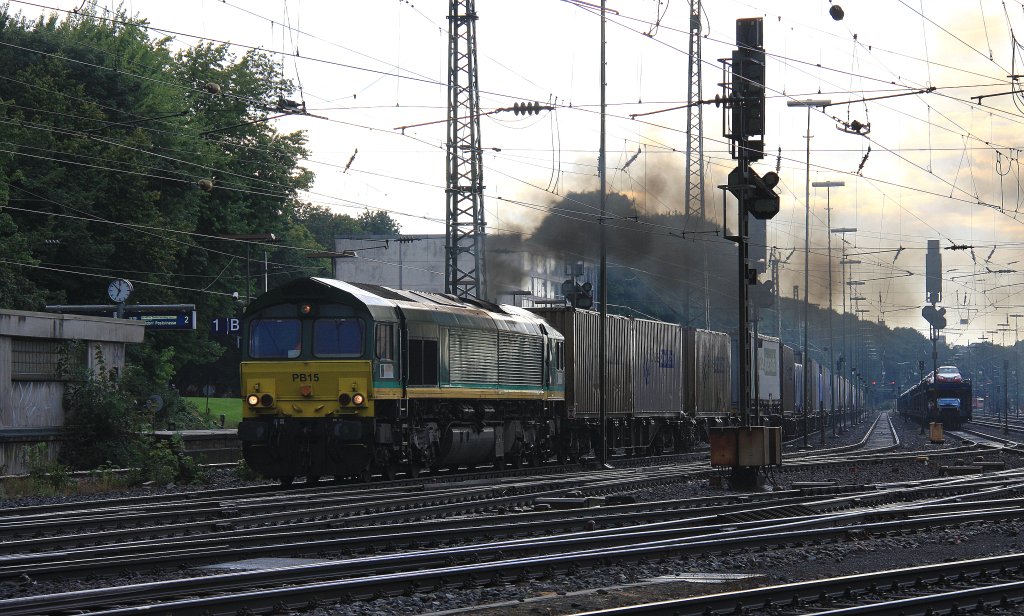 Die Class 66 PB15 von Railtraxx BVBA fhrt mit viel Rauch mit einem Containerzug aus Novara(I) nach Genk-Zuid-Haven(B) bei der Ausfahrt von Aachen-West und fhrt in Richtung Montzen/Belgien in der Abendstimmung am 26.8.2012.