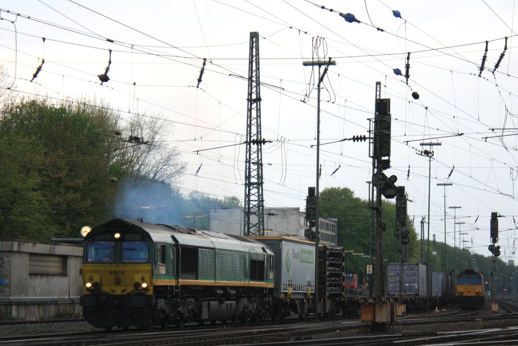 Die Class 66 PB15 von Railtraxx BVBA fhrt viel Qualm mit einem langen Containerzug aus Novara(I) nach Genk-Zuid-Haven(B) bei der Ausfahrt aus Aachen-West und fhrt in Richtung Montzen/Belgien und im Hintergrund steht eine Class 66 DE6309 von DLC Railways mit einem langen MSC-Containerzug in der Abendstimmung am 1.5.2013.