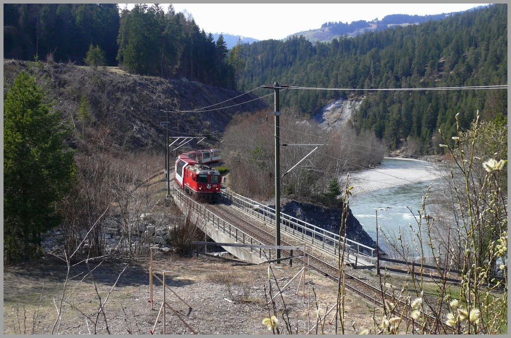 Die Haselstrucher blhen, was besonders Allergiker freut und der GlacierExpress 910 mit Ge 4/4 II 623  Bonaduz  fhrt bei Valendas ber den Carrerabach. Diese Brcke wird in Krze um drei Meter hher neu gebaut, um besser gegen berflutungen geschtzt zu sein. (08.04.2010)