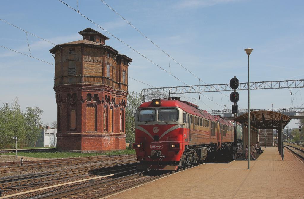 Die litauische Doppellok 2M62 1161 ist am 29.4.2012 mit einem schweren Kesselwagenzug in Richtung Kaunas unterwegs und passiert gerade den 
imposanten Wasserturm im Bahnhof Kaisyadoris. 