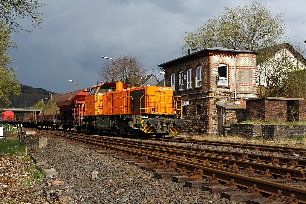 Die Lok 46 der KSW (Kreisbahn Siegen-Wittgenstein), eine Vossloh G 1700 BB (eingestellt als 92 80 1277 807-4 D-KSW),  mit dem Gterzug geht es am 16.04.2012 vom KSW-Gleis aufs DB-Gleis, hier vorbei am Stellwerk Herdorf Ost (Ho), in Richtung Betzdorf/Sieg zur bergabefahrt.