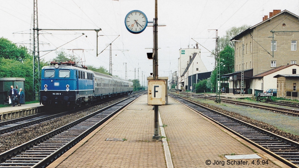 Die noch blaue 110 235 hlt am 13.7.98 mit ihrem E 3439 nach Nrnberg in Markt Bibart. Damals hatte der Bahnhof noch drei Gleise und einen Mittelbahnsteig, 12 Jahre (auf Bild 489727) sollte die rechte Bildhfte gleislos sein.