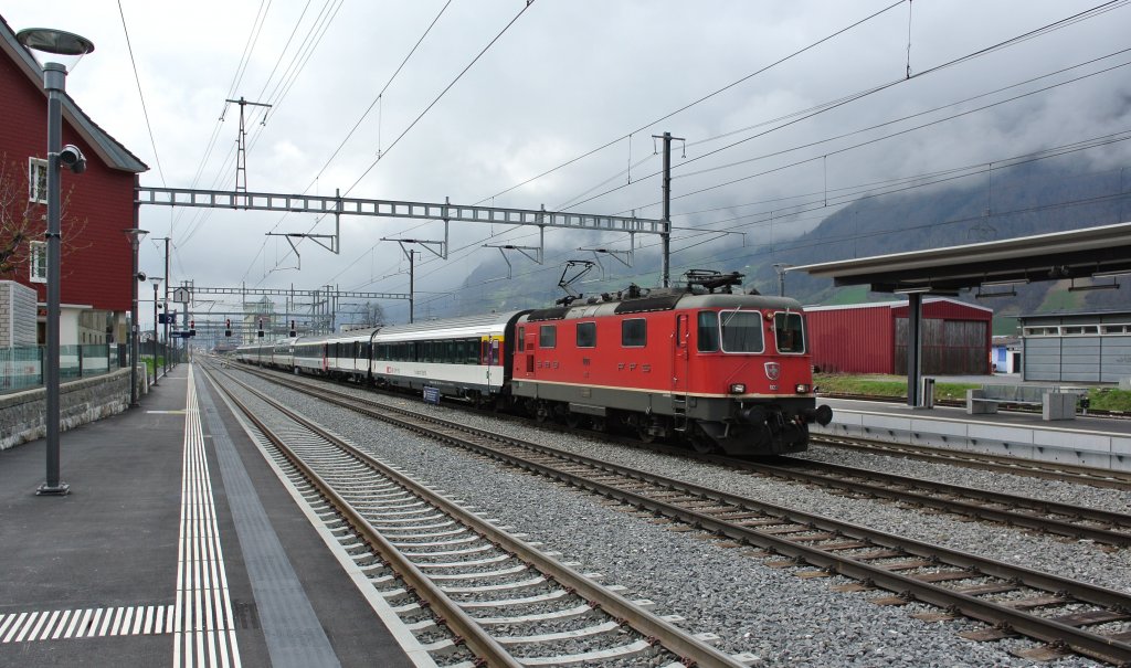 Die Re 4/4 II 11220 mit dem IR 2174 bei Durchfahrt in Altdorf. An der Spitze des Zuges ist der Wilhelm Tell Express Wagen, 06.04.2012.