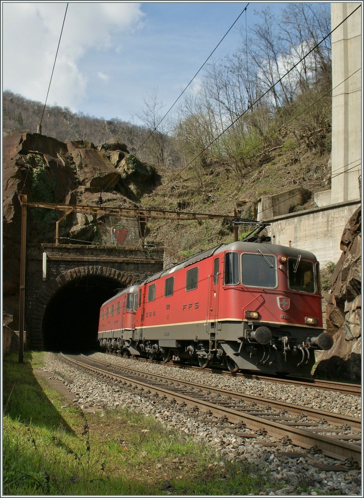 Die Re 4/4 II 11392 und eine Re 6/6 verrlassen mit einem Gterzug den 72m langen Tournquet Tunnel bei der alten Blockstation Pianotondo. 3. April 2013