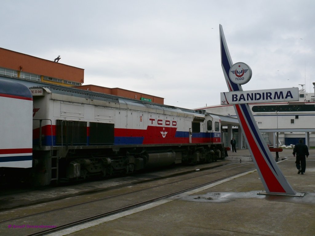 Die TCDD DE33040 im Bahnhof von Bandirma.
Die 20,74 Meter lange Co´Co´-Diesellok wurde 2006 von Tlomsas in Lizenz von EMD gebaut.
Im Hintergrund liegt eine Fhre, die Bandirma ber das Marmarameer mit Istanbul verbindet.
15.04.09  Bandirma
