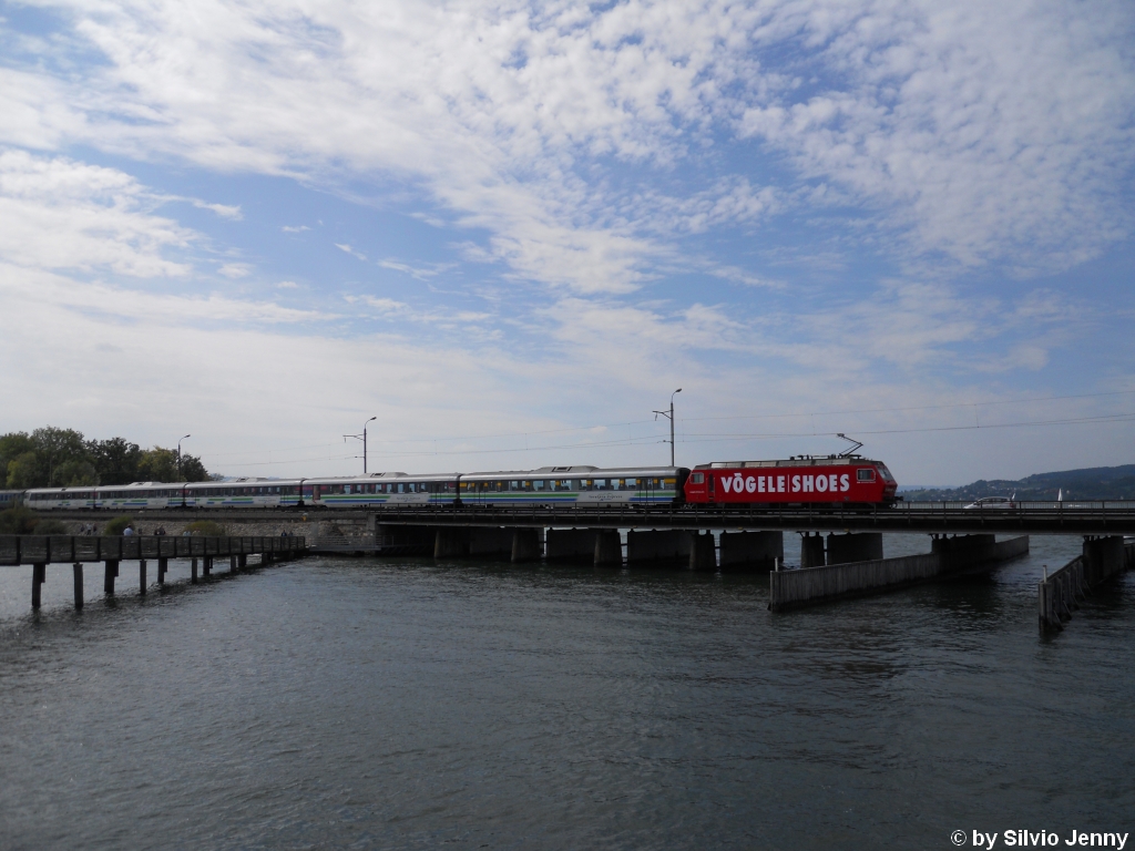 Die Werbung der Re 456 094-2 ''Vgele Shoes'' erhielt im Sommer 2010 ein neues Design. Am 5.9.2010 berquert sie mit einem Voralpen-Express nach romanshorn auf dem Rapperswiler Seedam den Zrichsee.