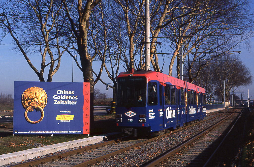 Dortumnd Tw 139 trug Ende 1993 eine Werbung fr eine Ausstellung Chinesischer Kulturgter. Vorbei an einem passenden Plakat fhrt der Wagen von Aplerbeck in Richtung Stadtmitte. Selten war der Einsatz von Solo-Tw auf der Aplerbecker Linie. Aufnahme am Westfalendamm vom 19.11.1993.