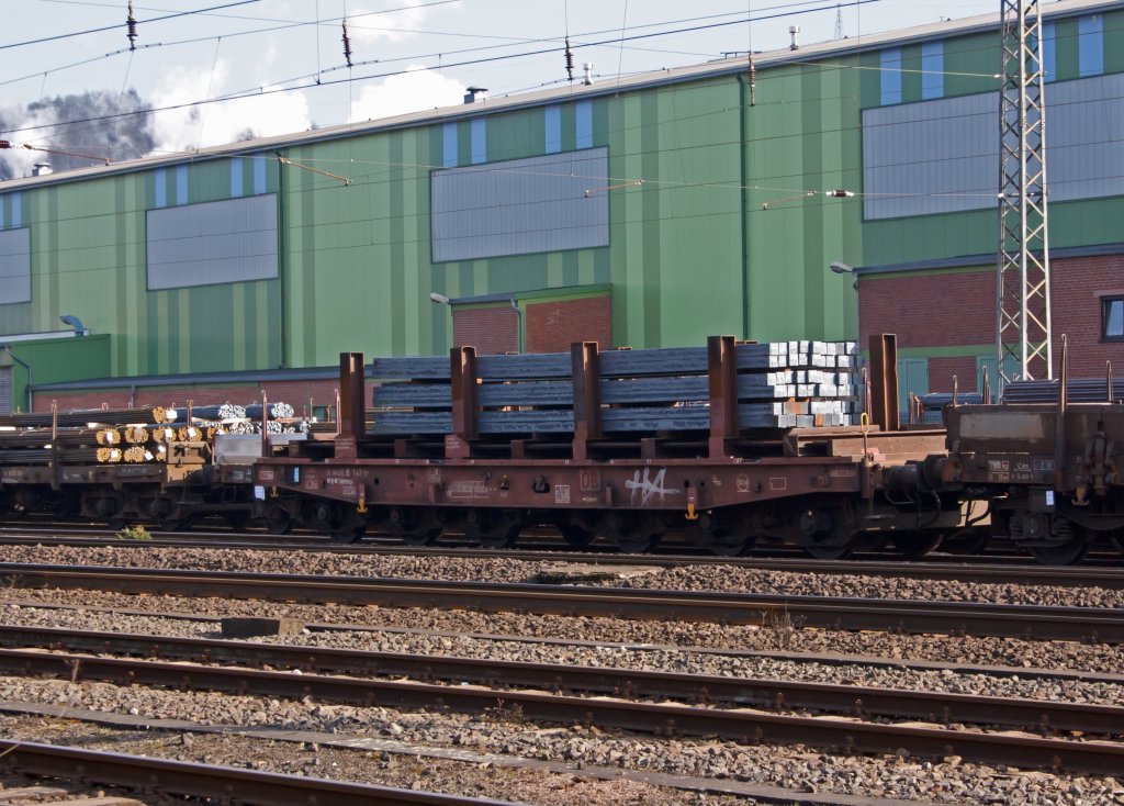 Drehgestellflachwagen (Schwerlastwagen) mit sechs Radstzen, ohne Seiten-, Stirnwnde und ohne Rungen (Salmmnps) abgestellt am 21.02.2011 auf den Werksgleis der Deutschen Edelstahlwerke (DEW) in Siegen-Geisweid. Der Wagen ist beladen mit Edelstahlknppel, im einem aufgesetzten Gestell liegen.