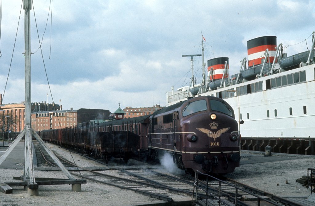 DSB Mx 1016 mit Personenwagen hlt am 27. April 1973 im Kopenhagener Freihafen (Bahnhof Frihavnen). - Rechts liegt das Fhrschiff nach Malm in Schweden. - Ungefhr in der Mitte des Bildes ragt der Turm des Bahnhofs auf. Das Gebude steht heute unter Denkmalschutz.  