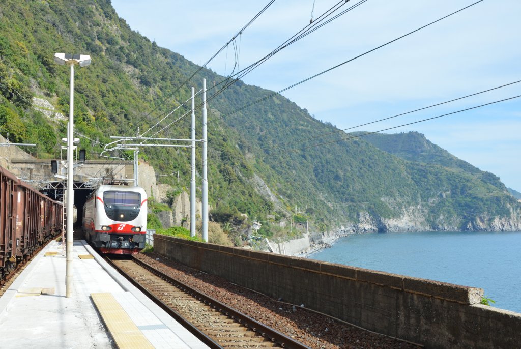 E402.174 (B) mit wohl verspteten IC-Zug fhrt durch Hp. Corniglia [Cinque Terre], Richtung Genova (Genua)/Nord. Im Hintergrund ist ltere Streckenfhrung der Ferrovia Ligure sichtbar; 09.05.2013