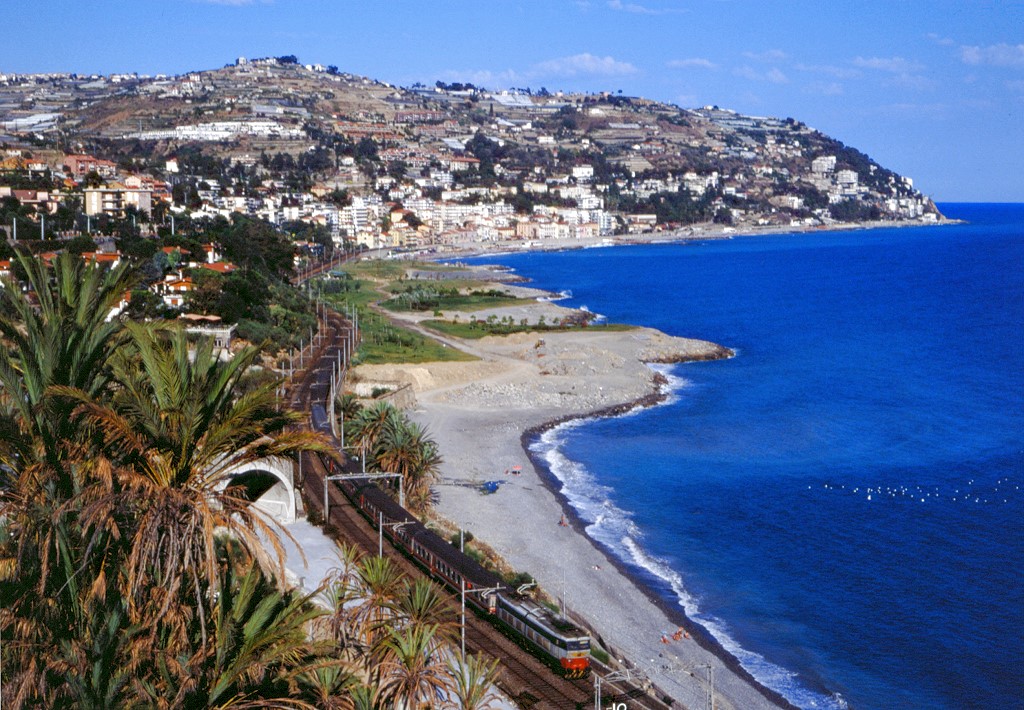 E656 473 bei Ospedaletti mit einem Zug in Richtung Ventimiglia, man sieht schon den Tunnel der spteren Neubaustrecke bei San Remo, 31.08.1990.