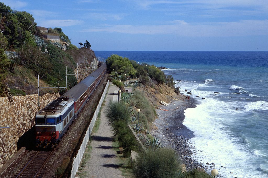 E656 544 mit einer klassischen italienischen Schnellzug-Garnitur als IR2186 bei San Lorenzo al Mare, 09.09.1994. Heute verluft die Bahntrasse begradigt und beschleunigt einige Hundert Meter weiter im Binnenland, Motive mit Bahn und Mittelmeer wie dieses sind nur noch selten mglich.