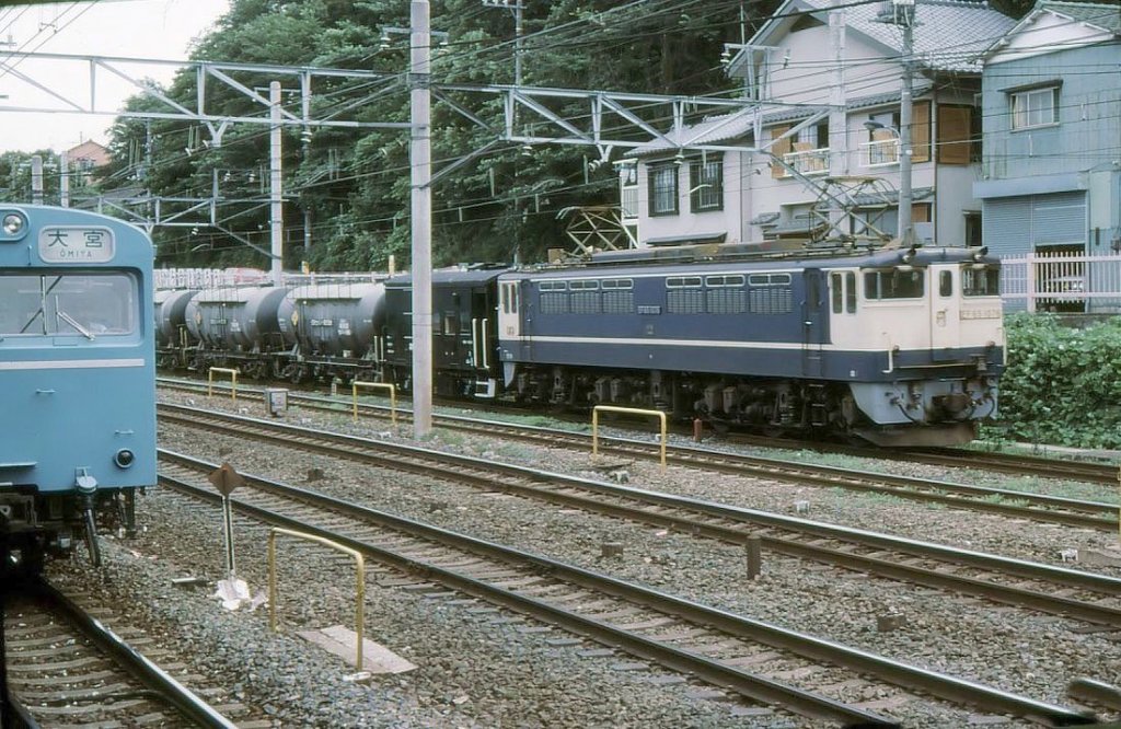 EF65 1000: Die letzten Serien EF65 wurden als Universalloks für Güter- oder Personenverkehr auf flachen Strecken und Einsatz in Doppeltraktion (deshalb die Stirnwandtüre) gebaut; Nr.1001-1055 1969-1972 und Nr.1056-1139 1976-1979. Heute sind sie alle der Güterbahn JR-Freight zugeteilt; einige sind schon ausgemustert. Hier fährt EF65 1076 durch Tokyo-Higashi Jûjô, 3.Juli 1979. 