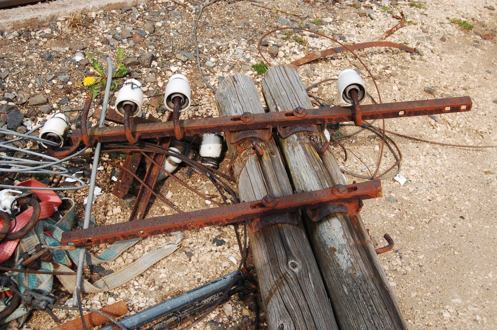 Ein  abgeholzter  Telegrafenmast liegt auf einem Bauplatz der Deutschen Bahn in Neustadt Aisch herum. Es fehlen leider schon viele Isolatoren.