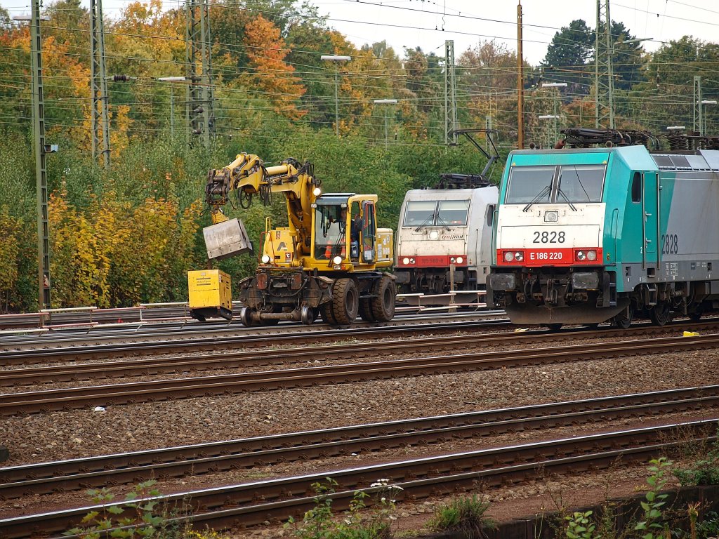 Ein Atlas 2Wegebagger von Eiffage Rail fhrt mit einem Stromaggregat an der Schaufel hngend zwischen den stehenden Loks 185 580-8 von Crossrail und der Cobra 186 220 am 22.10.2010 durch Aachen West.