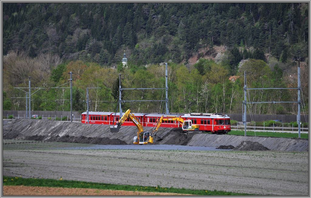 Ein Bagger grbt, der Andere schttet den Erdwall auf. So hofft man die Rfe von den Geleisen und der Autobahn fernzuhalten. S2 1556 mit Be 4/4 511 bei Felsberg. (27.04.2013)