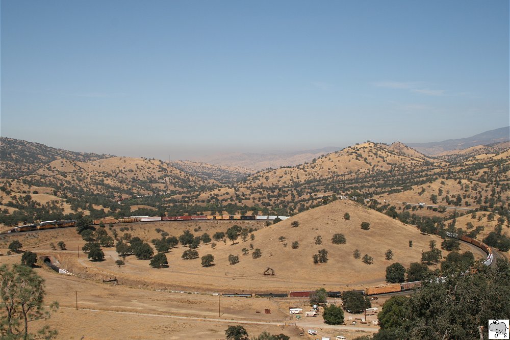 Ein bergauf fahrender gemischter Gterzug der Union Pacific schlngelt sich durch den Tehachapi Loop in Kalifornien. Die Zugloks # 5451 (GE AC45CCTE), # 4035 (EMD SD70M) und # 5306 (GE AC45CCTE) berqueren auf den Bild gerade ihren eigenen Zug.