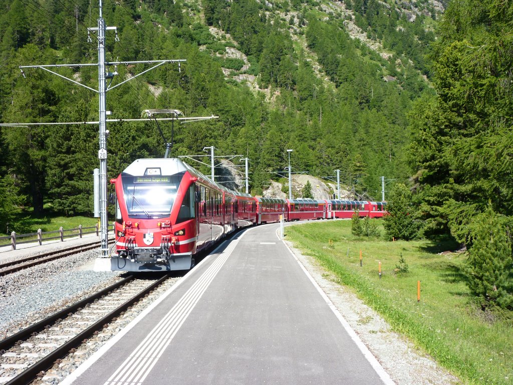 Ein Bernina Express wird am 3.7.2010 von einem neuen RhB Triebwagen dursch den Bahnhof Morteratsch nach Tirano gezogen.