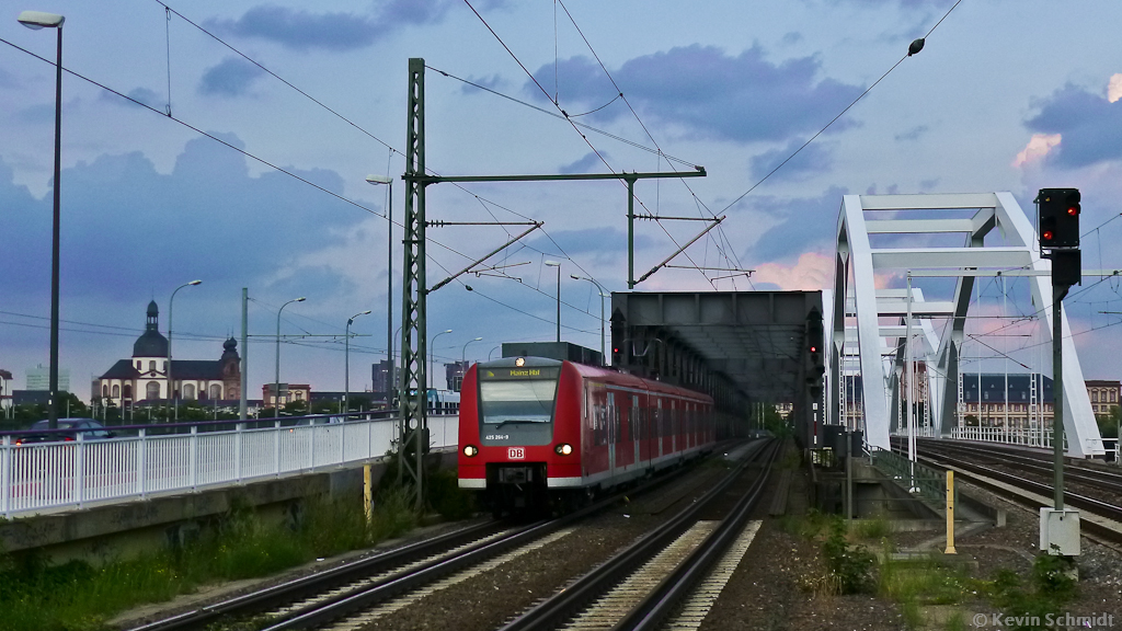 Ein ET 425 erreicht als RB von Mannheim-Friedrichsfeld nach Mainz Hbf in der Abenddämmerung nach der Überquerung des Rheins (und zugleich der Landesgrenze RP/BW) den Bahnhof Ludwigshafen (Rhein) Mitte. Auf der anderen Rheinseite ist die Stadt Mannheim zu sehen. (28.07.2012)