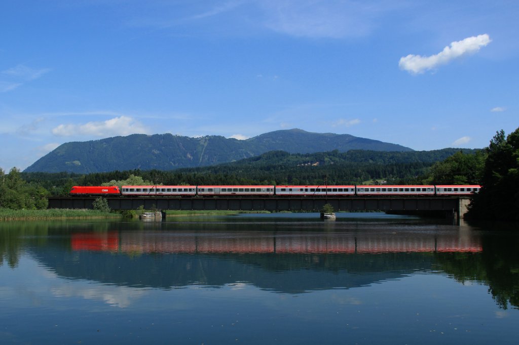 Ein BB Taurus zieht einen OIC von der Sdbahn kommend nach Villach Hbf, hier aufgenommen mit Spiegelung auf einer Brcke bei St. Ulrich kurz vor Villach am 08.06.12.