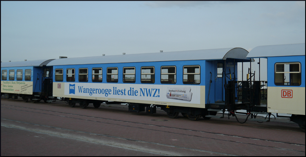Ein Personenwagen der Wangerooger Inselbahn steht in einem der beiden Wagengarnituren eingereiht am Westanleger und wartet auf neue Fahrgste. Der Wagen 63 212 wurde am 23.06.93 per Schiff auf die Inselbahn gebracht und aufgrund des harten Seeklimas 2001 im Dampflokwerk generalberholt. Einige Wagen tragen Werbung fr verschiedene Unternehmen auf der Insel. (28.08.2012)