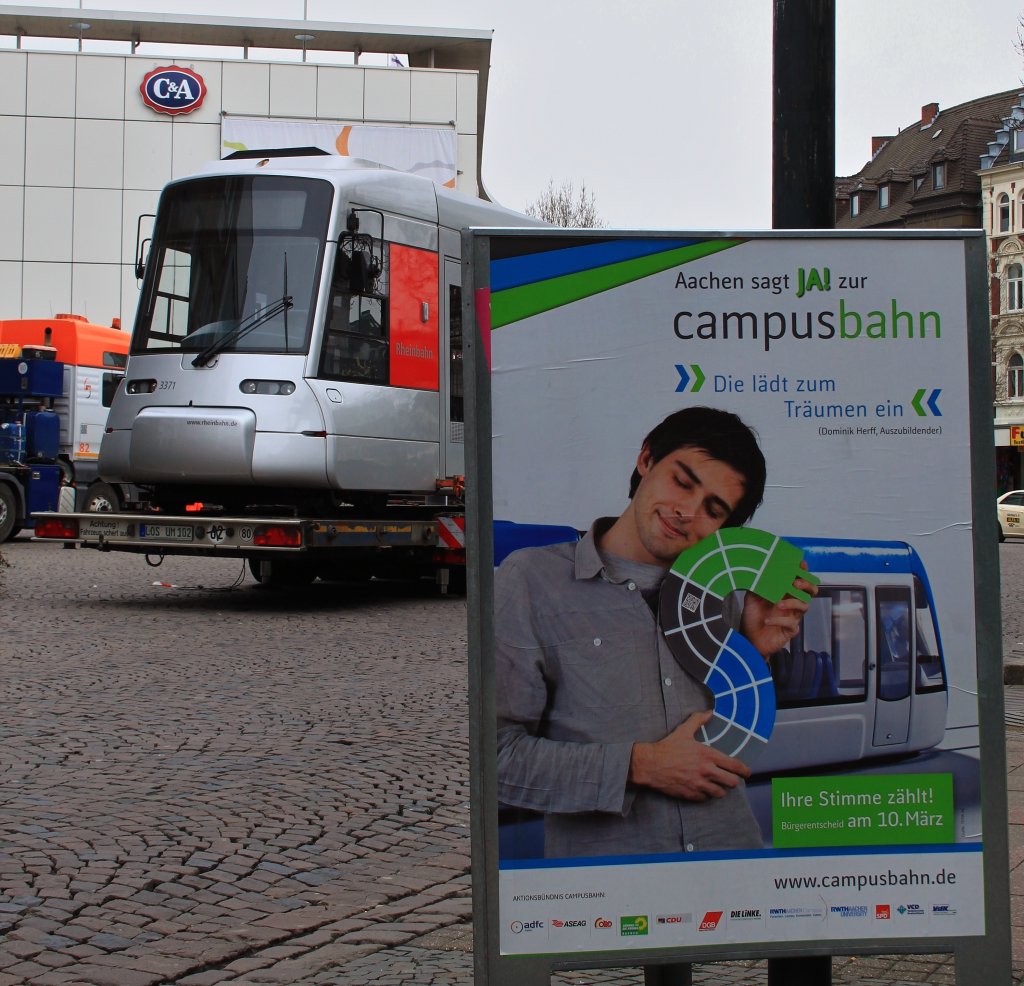 Ein Traum knnte wahr werden. Am 10. Mrz 2013 werden die Aachener in einem Brgerentscheid bestimmen ob hier eine neue Stadtbahn gebaut wird. Bis mitte der 70er Jahre gab es hier eine Strassenbahn mit einem groen Schienennetz, das immer weiter zurckgebaut wurde um die Stadt Autofreundlicher zu machen. 
Geplant ist in der ersten Bauphase eine ca.12,5 Kilometer lange Trasse, die von Aachen-Brand durch den Stadtkern von Aachen ber den neuen Campus der RWTH zum Klinikum fhrt. Die Kosten werden mit ca. 240 Mio. Euro veranschlagt, wovon die Hlfte von Bund und Land finanziert werden. Mit Zinsen, Tilgung und Betriebskosten wrden etwa 4,0 - 6,5Mio. Euro jhrlich anfallen. Diese Zahlen haben hier in Aachen viele Brger verunsichert. Es hat sich unter anderem eine Brgerinitiative  Campusbahn=Grenwahn  gegrndet die dieses Projekt scheitern lassen will. Ich hoffe sehr das sich die Aachener fr eine Stadtbahn entscheiden, es wre schade so eine Gelegenheit ungenutzt zu lassen und eine Umweltfreundliche und attraktive Nahverbindung zu bauen. 
 Ach ja, im Hintergrund steht am 03.03.2013 Triebwagen 3371 der Rheinbahn aus Dsseldorf auf dem Willy Brand Platz auf einem Tieflader um fr die Campusbahn zu werben.