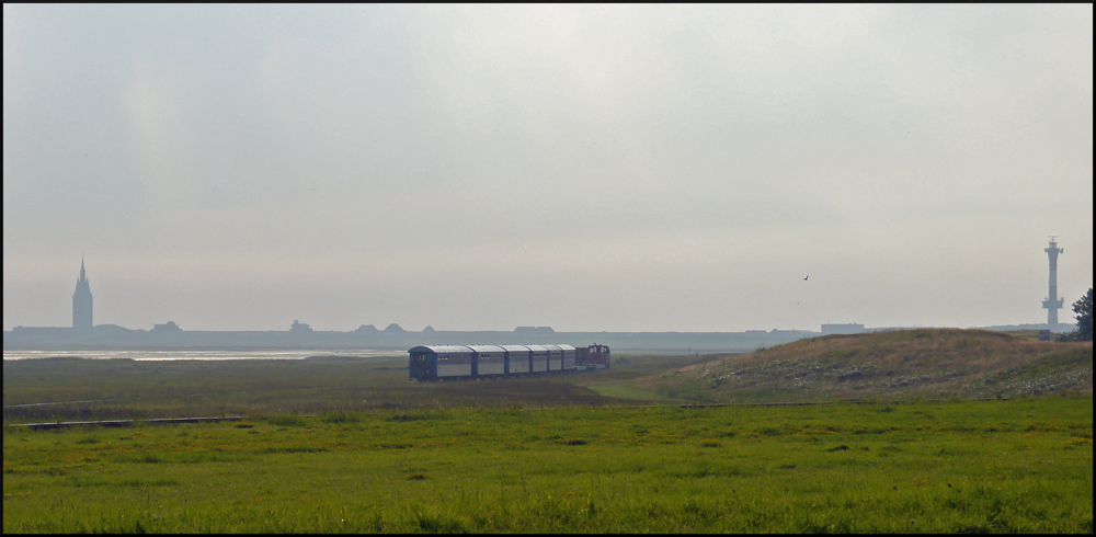 Ein typisches Panorama für die Wangerooger Inselbahn; links der als Landschulheim genutzte Westturm und rechts der moderne Leuchtturm, der einzige der auf Wangerooge noch in Betrieb ist. Die Inselbahn fuhr das letzte mal an diesem Tag zum Westanleger, während die Dämmerung einbrach. (28.08.2012)