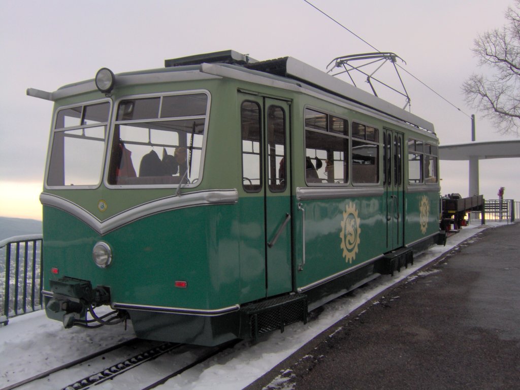 Ein Zahnradtriebwagen der Drachenfelsbahn der einen Gterwagen am Haken schleppt.