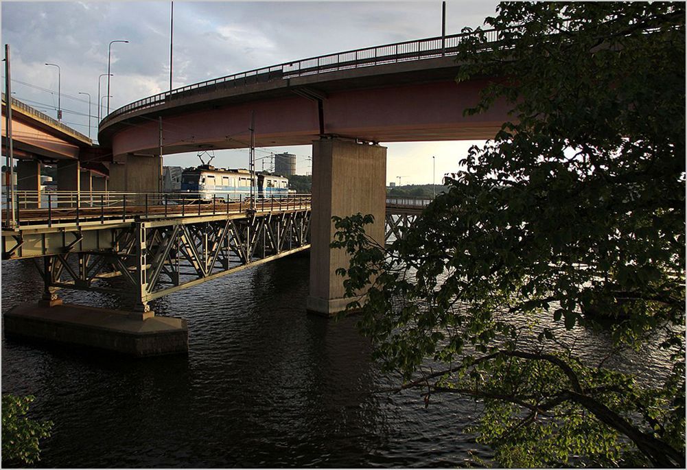 Ein Zwei-Wagen Zug der Lidingbanan im Abendlicht des 25. Juli 2012 kurz nach der berquerung der noch sichtbaren Lidingbrcke in Liding/Torsvik. 