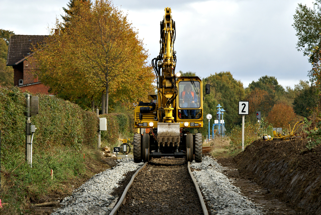 Ein Zwei-Wege-Bagger am 17.10.2009 in Hohenwestedt. auf der linken Seite ist das Bahnhofsgebude zu erahnen.Das Bild entstand von einem geffneten Bahnbergang.