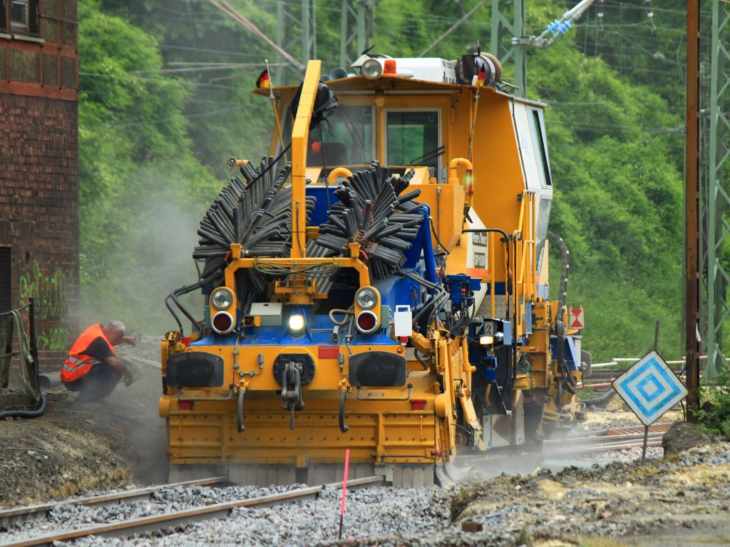 Ein zweiter Mann weist den Fahrer der Schotterplaniermaschine an der Weiche vom Streckenrand ein. Am 04.07.2012 planiert eine SSP 110 SW von der Deutschen Gleisbau Union in Aachen West.