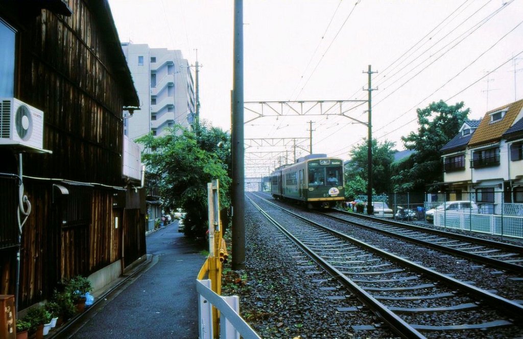 Ein Zweiwagenzug, gefhrt vom noch grnen Wagen 613, mitten in der Stadt Kyoto bei Mibu, 11.Juli 1997. 