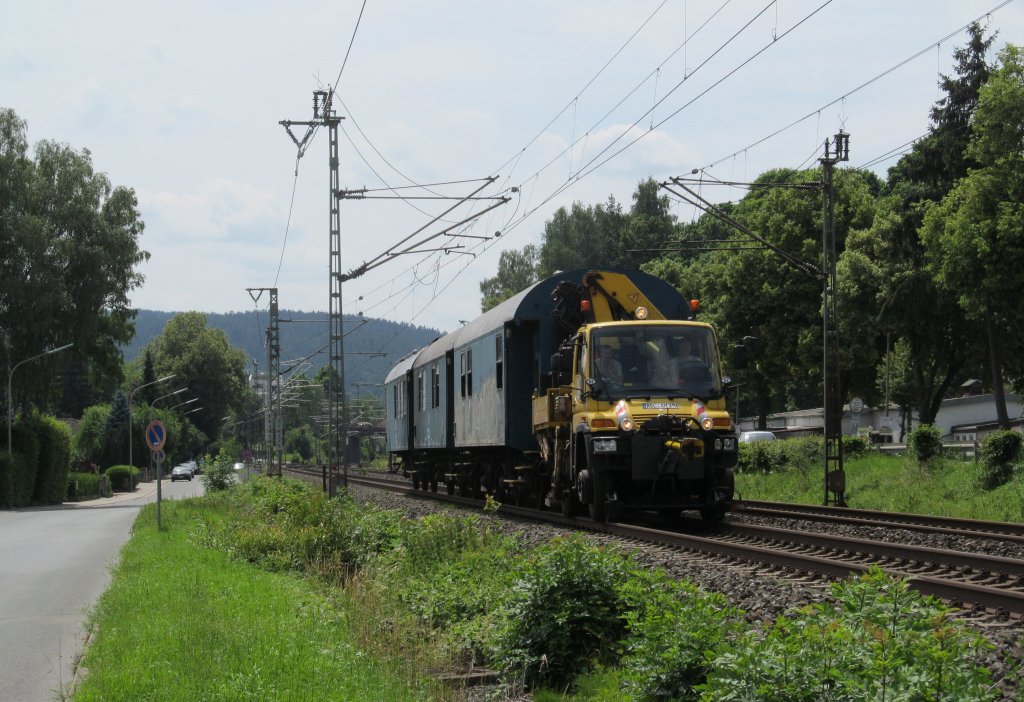 Ein Zweiwege Unimog des Road und Rail Service zieht am 24. Juni 2012 drei Bauzugwagen durch das Kronacher Stadtgebiet.