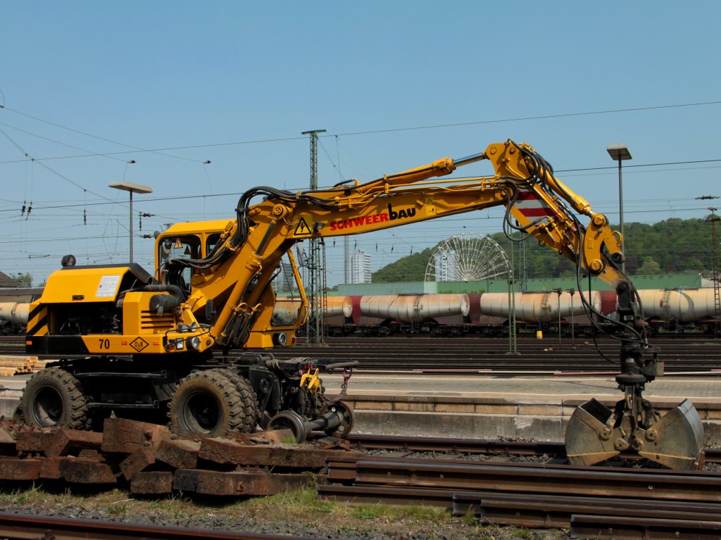 Ein Zweiwegebagger von Schweerbau am 22.04.2011 an dem Gleisanschlu vom Institut fr Schienenfahrzeuge (IFS) der RWTH Aachen in Aachen West. Unter dem Arm des Baggers sieht man im Hintergrund noch das Riesenrad des  Oecher Frhjahrsbend .