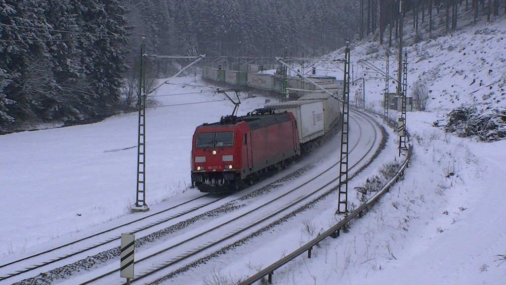 Eine BR 185 der DB ist am 28.01.2012 mit dem Hangartner / DB Schenker KLV aus Verona Q. E. nach Rostock Seehafen auf der Frankenwaldbahn zwischen Frtschendorf und Steinbach am Wald unterwegs.