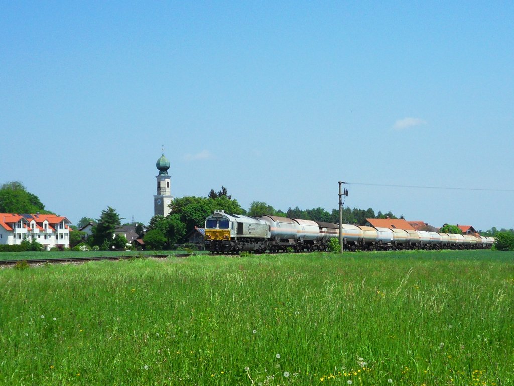 Eine Class 66 fhrt am 15.05.2012 mit ihrem Kesselwagenzug aus Richtung Burghausen kommend am Kirchturm von Heiligenstatt vorbei.