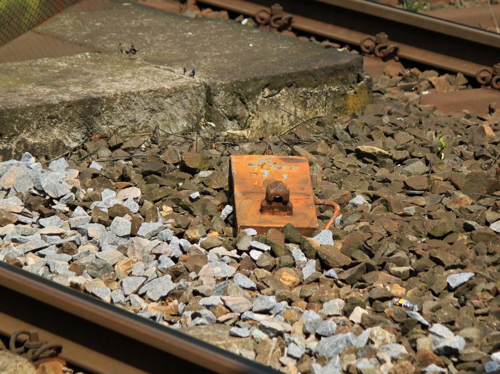 Eine von einem Containertragwagen verlorene Containerverriegelung samt Fundamentplatte am 09.08.2012 im Schotter zwischen den Gleisen im Haltepunkt Aachen Schanz. 