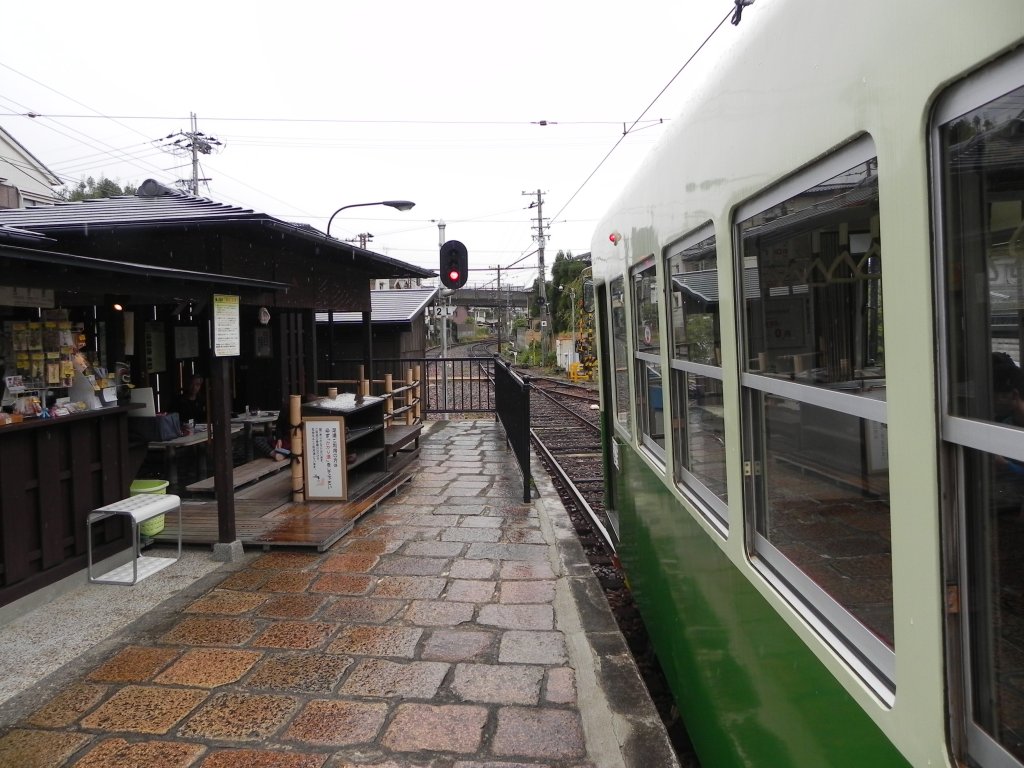 Eine etwas unbliche Sicht in die Richtung, in die der Triebwagen der Randen Tram aus der Station  Arashiyama  gleich ausfahren wird. Links ist eine Besonderheit zu erkennen: Ein Fuss-Onsen, also eine durch eine heisse Quelle gespeiste Art  Fussbad , wo gestresste Touristen ihre Fsse entspannen knnen. Daneben einer der in dieser Gegend omniprsenten Souvenierlden.