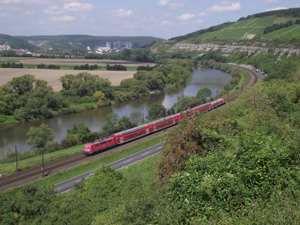 Eine Mchnener Doppelstock Garnitur und ein Wrzburger Bduu sind am 2. August 2011 im 111er Sandwich als RE von Wrzburg nach Frankfurt am Main bei Karlstadt am Main unterwegs.