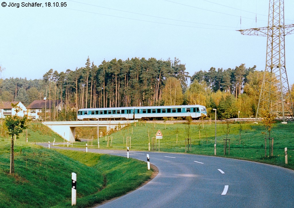 Eine RB nach Pleinfeld fhrt am 18.10.95 ber die damals neue Straenbrcke in den Haltepunkt Ramsberg ein. Der Bahnsteig liegt rechts vom Zug hinter dem Hochspannungsmast.