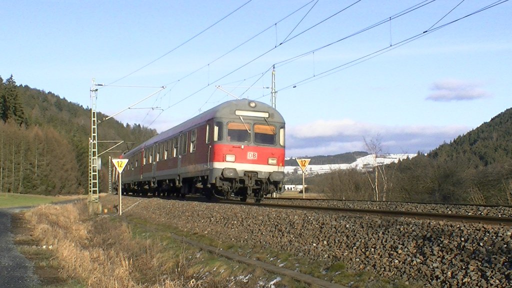 Eine Regionalbahn mit Karlsruher Steuerwagen, ein weiterer n-Wagen und eine BR 111 am Zugschluss sind am 15.01.2011 auf der Frankenwaldbahn zwischen Pressig-Rothenkirchen und Stockheim unterwegs. Im Hintergrund sieht man die Hhenzge des Frankenwaldes, ber die auch die KBS 840 (Frankenwaldbahn) fhrt. 